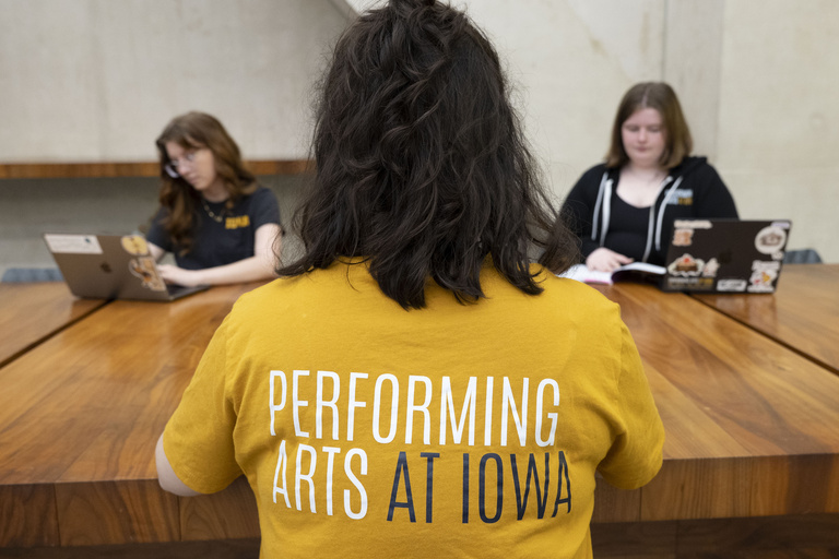 Students sitting at a table wearing a variety of Performing Arts At Iowa merch